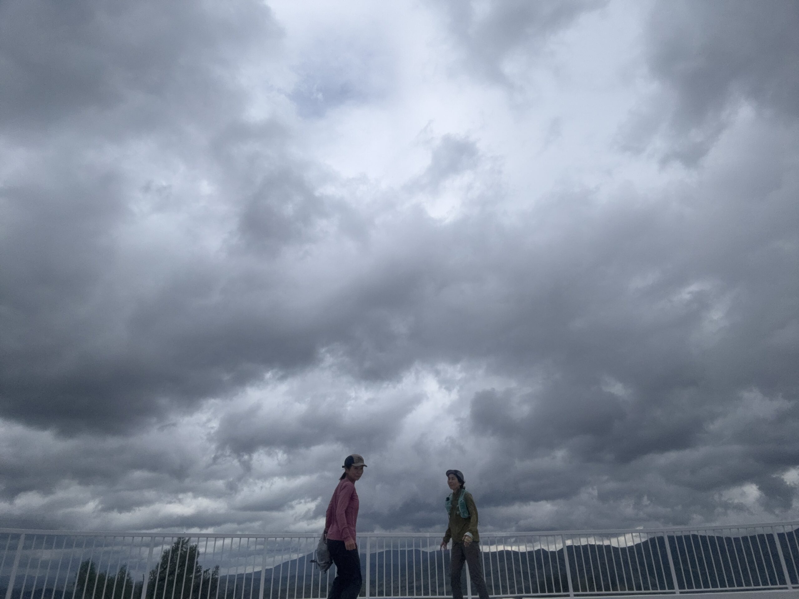 曇り空の下、橋の上に2人が立つ写真